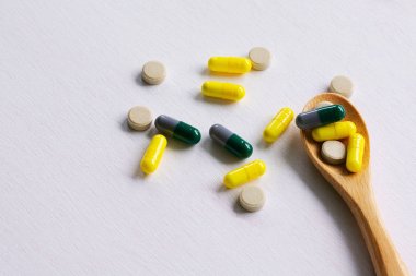 Tahta kaşıkta çeşitli ilaç hapları, tabletler ve kapsüller.