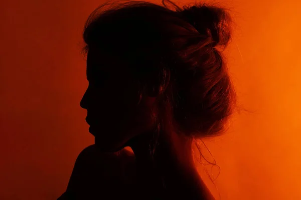 Siluet seorang gadis di studio dengan latar belakang merah. Photoshoot. Studio Foto . — Stok Foto