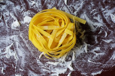 Karanlık bir arka planda pişmiş makarna, un ile serpilir, haddeleme pin yakın