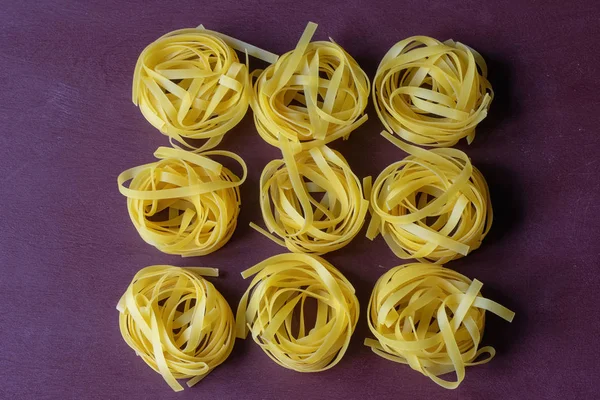 Trockene Nudeln gelb auf dunklem Hintergrund. italienisches Essen — Stockfoto