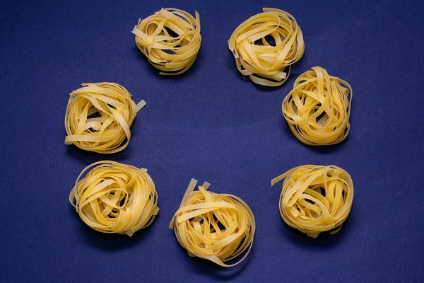 Trockene Nudeln gelb auf dunklem Hintergrund. italienisches Essen — Stockfoto