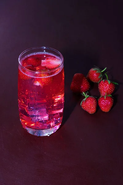 Drink with ice from strawberries on a dark background. Fresh strawberry cocktail. Fresh summer cocktail with strawberry and ice cubes. Glass of strawberry soda drink on dark background. — Stock Photo, Image