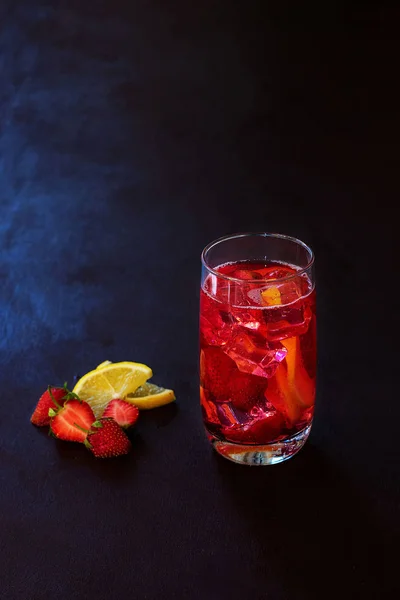 Beba com o gelo de morangos em um fundo escuro. Cocktail de morango fresco. Cocktail fresco de verão com cubos de morango e gelo. Copo de refrigerante de morango no fundo escuro . — Fotografia de Stock