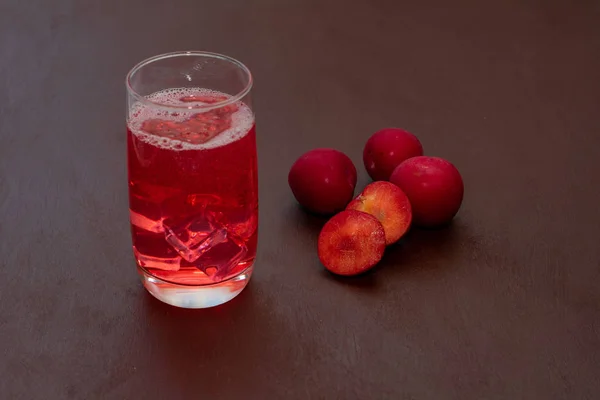 Drink met ijspruim op een donkere achtergrond. Verse pruim cocktail. Frisse zomer cocktail met pruimen en ijsblokjes. Een glaasje pruim soda drankje op een donkere achtergrond. — Stockfoto