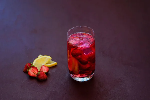 Beba com o gelo de morangos em um fundo escuro. Cocktail de morango fresco. Cocktail fresco de verão com cubos de morango e gelo. Copo de refrigerante de morango no fundo escuro . — Fotografia de Stock