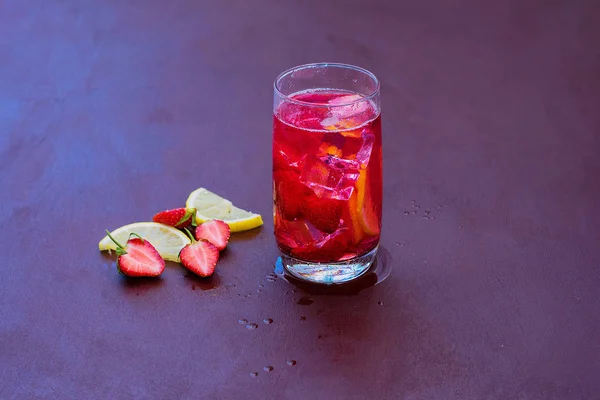 Beba com o gelo de morangos em um fundo escuro. Cocktail de morango fresco. Cocktail fresco de verão com cubos de morango e gelo. Copo de refrigerante de morango no fundo escuro . — Fotografia de Stock