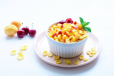 Mısır gevreği ve meyve parçaları ile sağlıklı kahvaltı, beyaz bir arka plan üzerinde kiraz