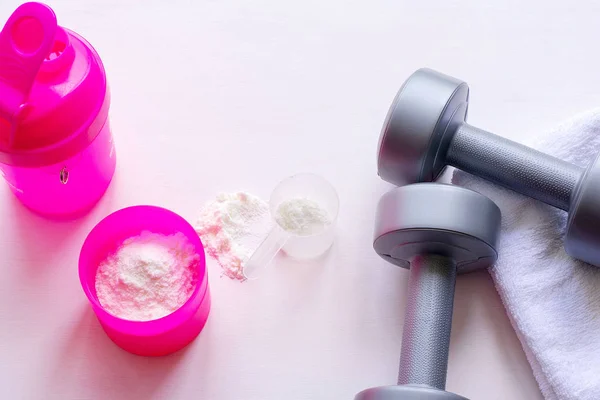 Protein shake, dumbbells and towel on white background