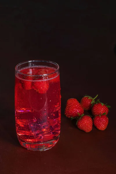 Drink met ijs uit aardbeien op een donkere achtergrond. Verse aardbeien cocktail. Frisse zomer cocktail met aardbei en ijsblokjes. Glas aardbei soda drankje op donkere achtergrond. — Stockfoto