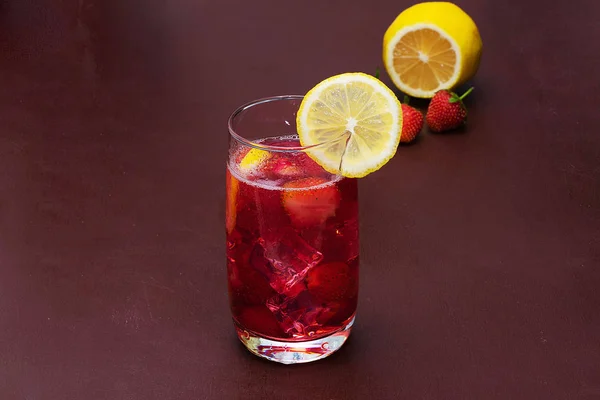 Beba com o gelo de morangos em um fundo escuro. Cocktail de morango fresco. Cocktail fresco de verão com cubos de morango e gelo. Copo de refrigerante de morango no fundo escuro . — Fotografia de Stock