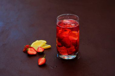 Koyu bir arka plan üzerinde çilek buz ile içilir. Taze çilek kokteyli. Çilek ve buz küpleri ile taze yaz kokteyli. Koyu arka planda çilekli soda içeceği.