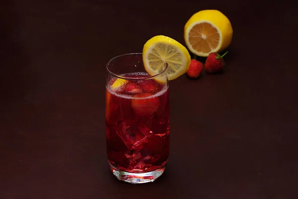 Beba com o gelo de morangos em um fundo escuro. Cocktail de morango fresco. Cocktail fresco de verão com cubos de morango e gelo. Copo de refrigerante de morango no fundo escuro . — Fotografia de Stock