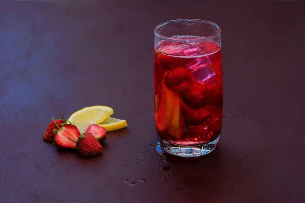 Beba com o gelo de morangos em um fundo escuro. Cocktail de morango fresco. Cocktail fresco de verão com cubos de morango e gelo. Copo de refrigerante de morango no fundo escuro . — Fotografia de Stock