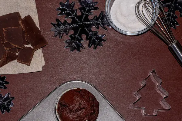 Pasteles e ingredientes sobre un fondo oscuro. Hornear un cupcake para Navidad — Foto de Stock