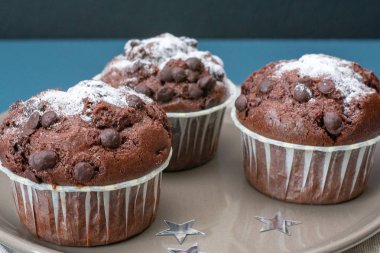 Üç çikolata kekler turkuaz renkli bir masanın arka planına karşı bir plaka üzerinde yatıyor. Kutlama. Doğum günü. Yılbaşı ve yeni yıl.