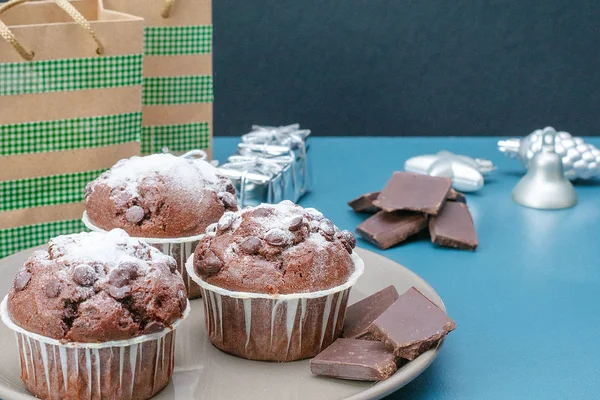 Tres magdalenas de chocolate yacen en un plato sobre el fondo de una mesa de color turquesa. Celebración. Navidad y Año Nuevo . — Foto de Stock