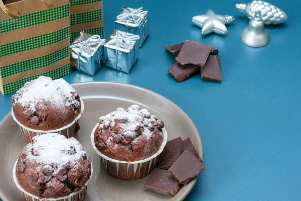 Tres magdalenas de chocolate yacen en un plato sobre el fondo de una mesa de color turquesa. Celebración. Navidad y Año Nuevo . — Foto de Stock