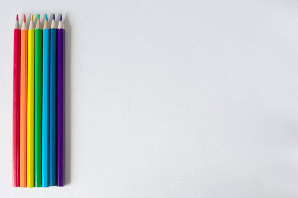 Many colored pencils lie on a white background. Copy spase. The concept of back to school, the educational process, study at school, drawing