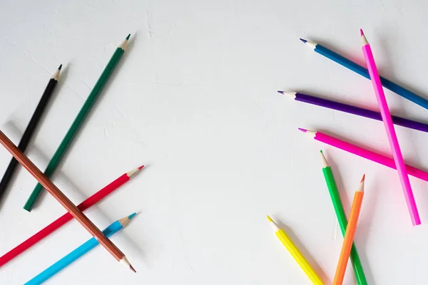 Muchos lápices de colores se encuentran sobre un fondo blanco. Recibido spase. El concepto de volver a la escuela, el proceso educativo, estudiar en la escuela, dibujar — Foto de Stock