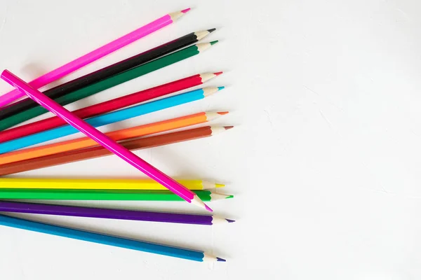 Muchos lápices de colores se encuentran sobre un fondo blanco. Recibido spase. El concepto de volver a la escuela, el proceso educativo, estudiar en la escuela, dibujar — Foto de Stock