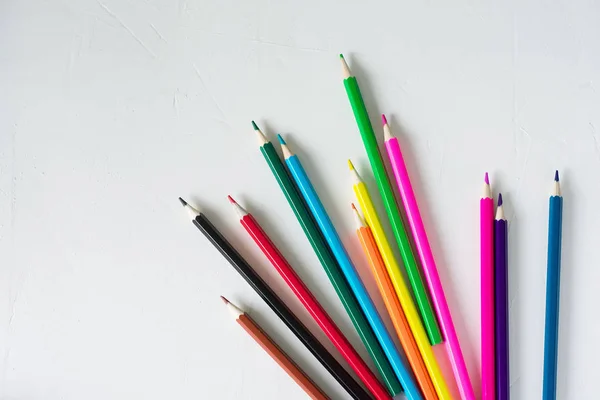 Many colored pencils lie on a white background. Copy spase. The