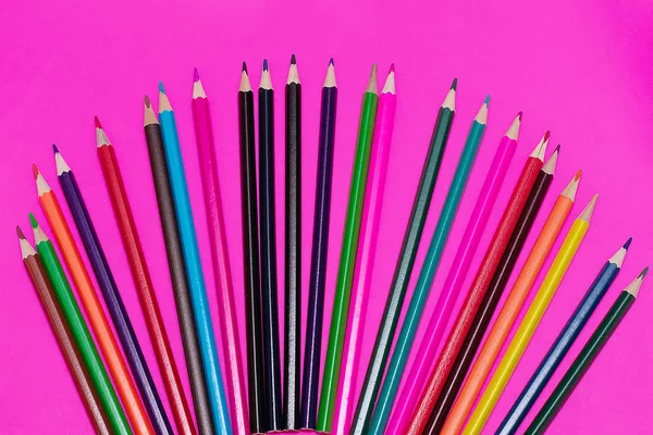 Muchos lápices de colores se encuentran sobre un fondo rosa. Recibido spase. El concepto de volver a la escuela, el proceso educativo, estudiar en la escuela, dibujar — Foto de Stock