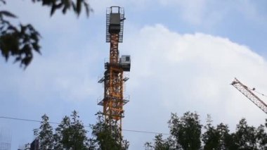 Bir inşaat vinç mavi gökyüzü ve bitmemiş bir bina karşı çalışır. Vinç montajı ile yüksek katlı bina