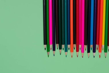 Birçok renkli kalemler yeşil bir arka plan üzerinde yalan. Spase'yi kopyala. Okula dönüş kavramı, eğitim süreci, okulda eğitim, çizim