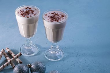 Tarçın ile iki ev yapımı eggnog milkshakes, dokulu mavi arka plan üzerinde Noel süslemeleri. Noel atmosferi