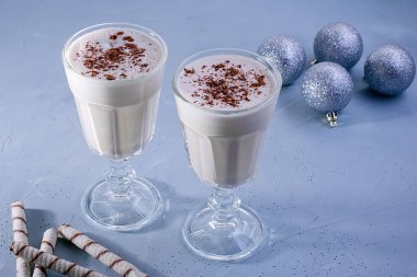 Tarçın ile iki ev yapımı eggnog milkshakes, dokulu mavi arka plan üzerinde Noel süslemeleri. Noel atmosferi