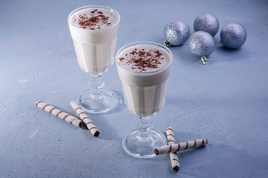 Tarçın ile iki ev yapımı eggnog milkshakes, dokulu mavi arka plan üzerinde Noel süslemeleri. Noel atmosferi