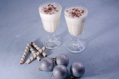 Tarçın ile iki ev yapımı eggnog milkshakes, dokulu mavi arka plan üzerinde Noel süslemeleri. Noel atmosferi