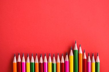 Duvar kağıdı olarak bir düz izole kırmızı arka plan üzerinde atış ile renkli pensils.