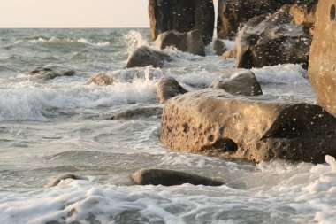 Deniz dalgaları sahilde kayaları vuruyor.