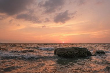 Deniz dalgaları sahilde kayaları vuruyor.