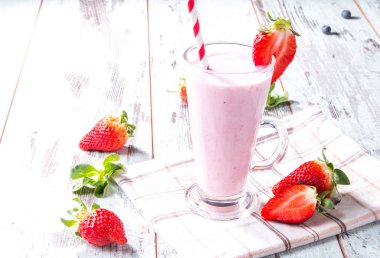 Taze süt, tahta masada çilek, taze meyveli çeşitli protein kokteylleri. Doğal arka plan