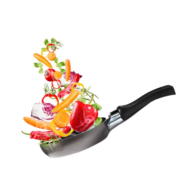 Frying pan with flying vegetables, isolated on white backfground  image