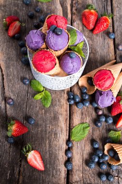 Ahşap arka plan üzerinde tatlı koni içinde dondurma kepçe. 