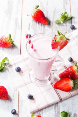 Taze süt, tahta masada çilek, taze meyveli çeşitli protein kokteylleri. Doğal arka plan.