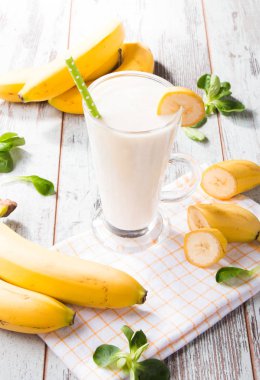 Taze süt, ahşap masada muz, taze meyveli çeşitli protein kokteylleri. Doğal arka plan.