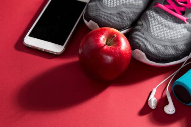 Spor ayakkabı, elma, meetr ve kırmızı arka plan üzerinde havlu çifti. Kopya alanı. Düz döşeme görüntüsü.