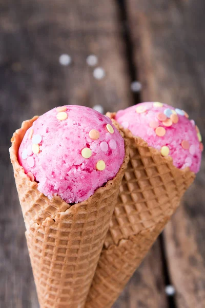 Ice cream scoops in sweet cone on wooden table