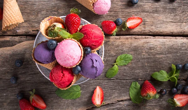 Ice cream scoops in sweet cone. Raspberry, blueberry and strawberry mix scoop. Sundae, summer concept.
