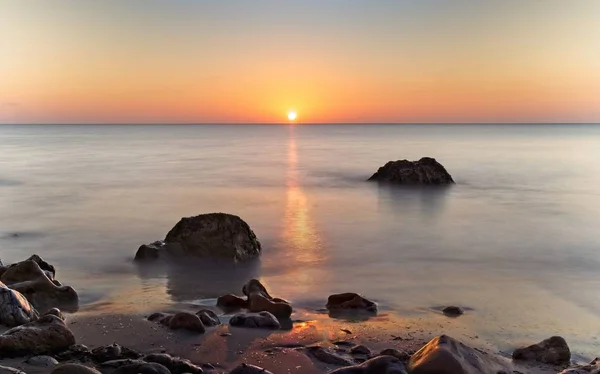 Nascer do sol com céu vermelho bonito, mar calmo com rochas em primeiro plano, port nou, cala bona, Maiorca, Espanha . — Fotografia de Stock