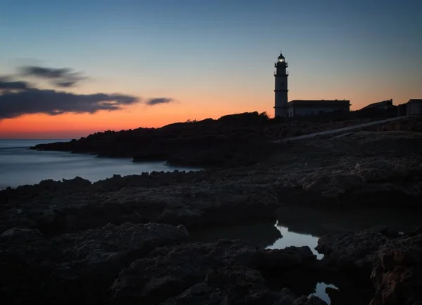 Lighthouse Far del cap ses salines at sunset, rocks, building, setting sun, beautiful golden sky, Maiorca, Espanha . — Fotografia de Stock