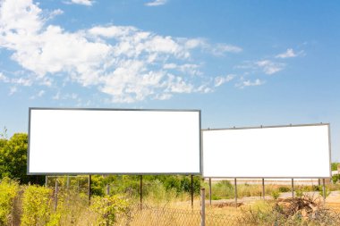 Tarlada bir yolun yanında iki reklam panosu ve bulutlu mavi bir gökyüzü. Yatay beyaz kopyalama alanı olan yatay resim