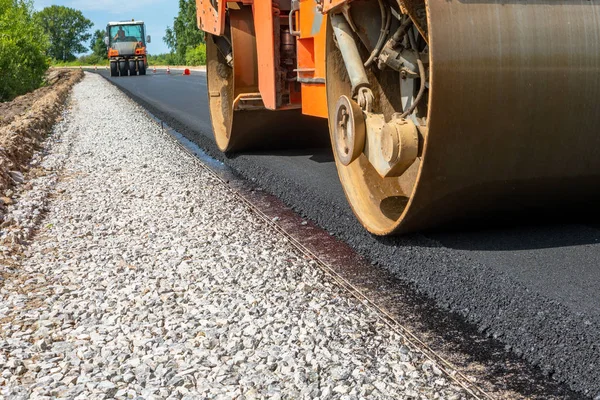 roller compacts asphalt on the road during the construction of the road. compaction of the pavement in road construction. rink goes on fresh asphalt. roller wheel closeup. hard work.