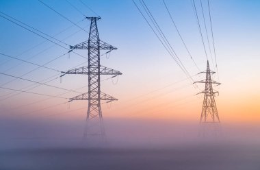 Şafak gökyüzü arka plan, siste enerji nakil direkleri. Yüksek gerilim güç satır yapısı gün batımı sırasında açık bir gökyüzünde