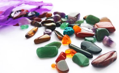 Çeşitli doğal parlak renkli yarı değerli taşlar ve çanta beyaz arka plan üzerinde mücevher