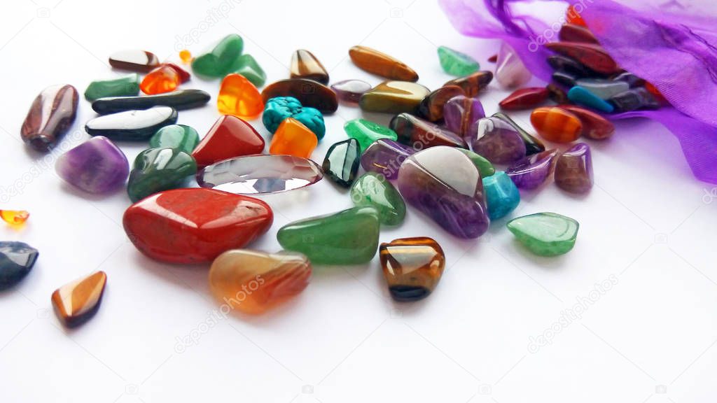 Assorted natural bright coloured semi precious gemstones and gems on white background